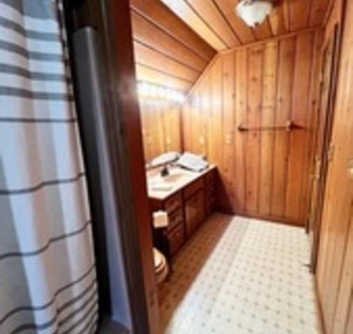 bathroom with wooden walls, wooden ceiling, and lofted ceiling