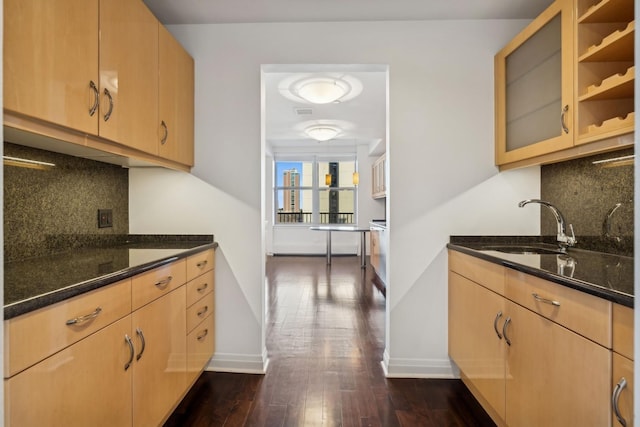 kitchen with sink, decorative backsplash, dark stone counters, and light brown cabinets