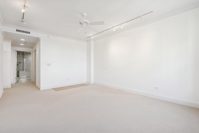 carpeted empty room with crown molding, rail lighting, and ceiling fan