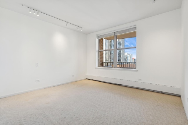 spare room featuring carpet floors, track lighting, and baseboard heating