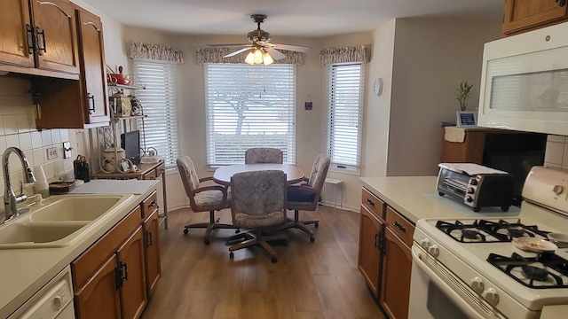 kitchen with ceiling fan, sink, white appliances, dark hardwood / wood-style floors, and decorative backsplash