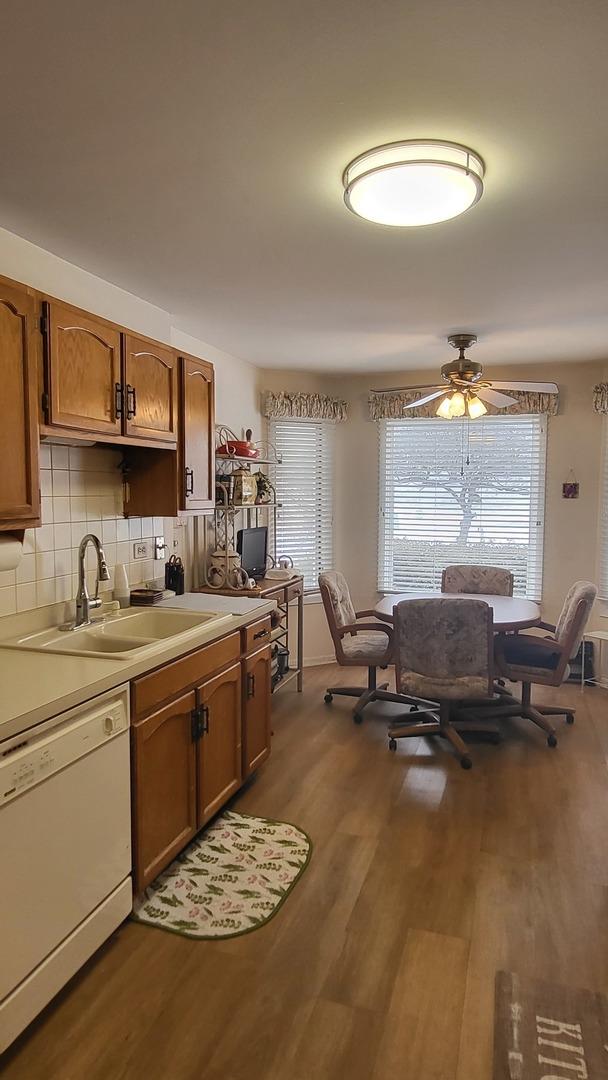 kitchen featuring ceiling fan, white dishwasher, sink, hardwood / wood-style flooring, and decorative backsplash