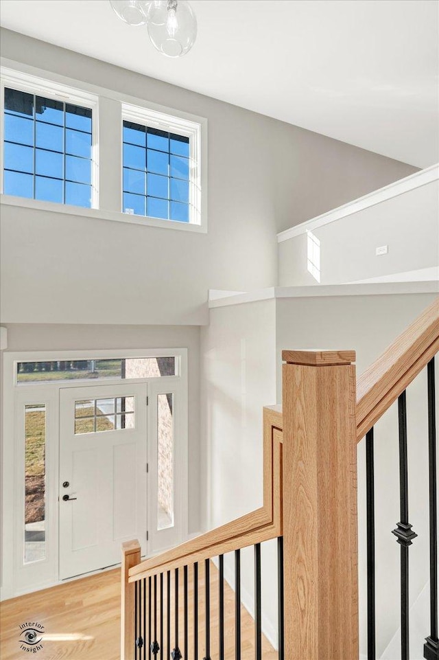 foyer entrance featuring stairs, light wood-style flooring, and a high ceiling