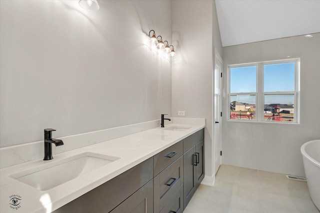 bathroom featuring a freestanding bath, double vanity, and a sink