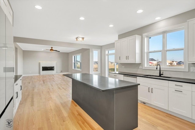 kitchen featuring sink, light wood-type flooring, white cabinetry, and a center island