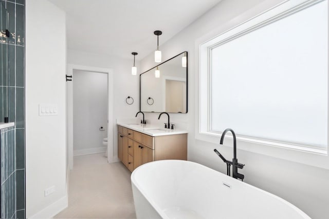 bathroom with vanity, a tub to relax in, and toilet