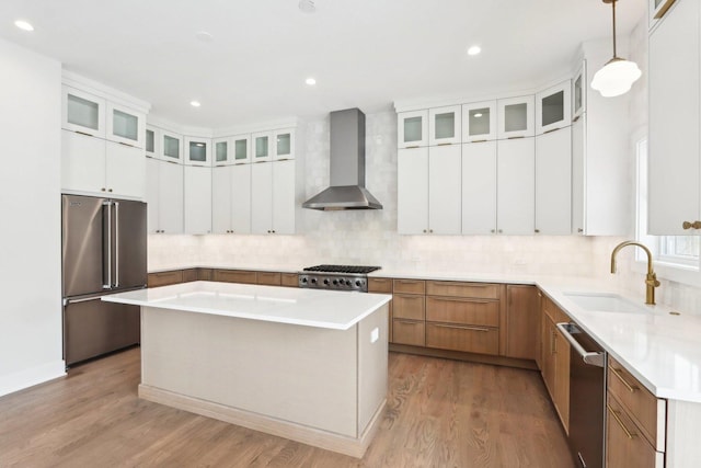 kitchen featuring pendant lighting, wall chimney range hood, a center island, and appliances with stainless steel finishes