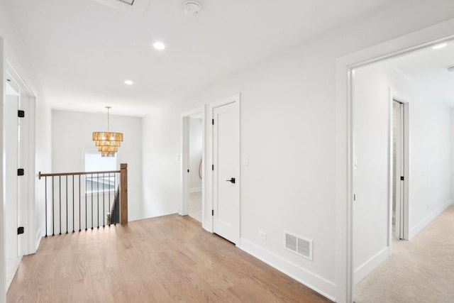 corridor with a chandelier and light hardwood / wood-style floors