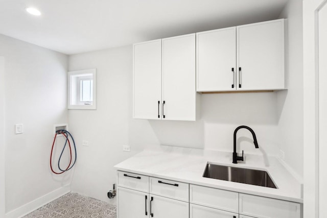 clothes washing area featuring hookup for a washing machine, sink, light tile patterned floors, and cabinets