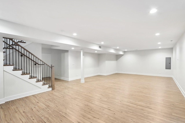 basement with electric panel and light hardwood / wood-style floors