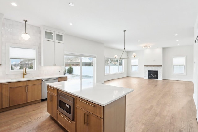 kitchen featuring sink, appliances with stainless steel finishes, white cabinetry, a center island, and decorative light fixtures