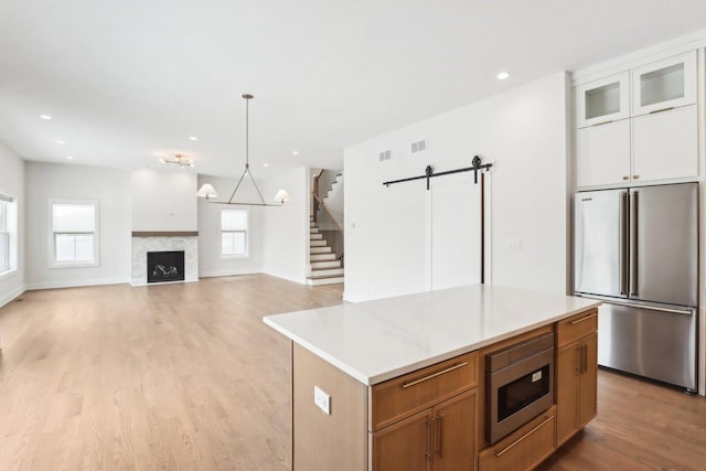 kitchen with white cabinetry, a center island, stainless steel appliances, a barn door, and light hardwood / wood-style floors