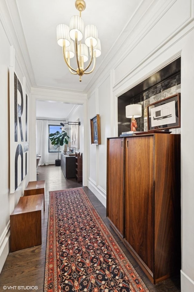 hallway featuring dark hardwood / wood-style flooring, ornamental molding, and a chandelier