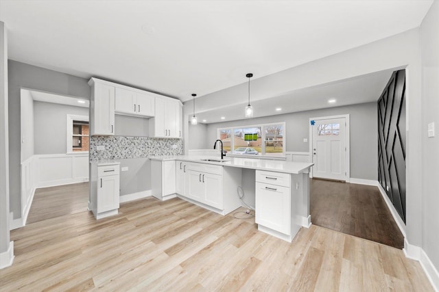 kitchen with white cabinets, kitchen peninsula, decorative backsplash, and sink