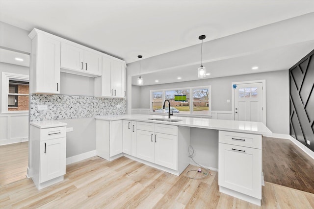 kitchen with sink, white cabinetry, hanging light fixtures, and tasteful backsplash