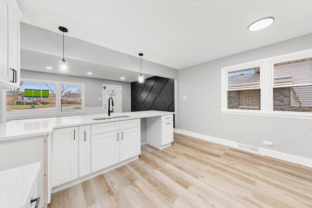 kitchen with sink, decorative light fixtures, white cabinets, and light hardwood / wood-style floors