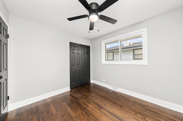 unfurnished bedroom featuring a closet, ceiling fan, and dark hardwood / wood-style flooring