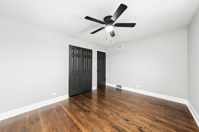 unfurnished bedroom with ceiling fan and dark wood-type flooring