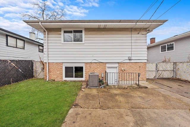 rear view of house with central AC and a yard