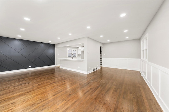 unfurnished living room featuring sink and hardwood / wood-style floors