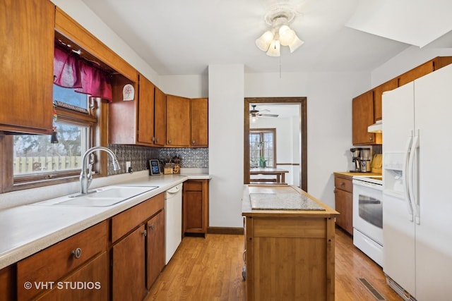 kitchen with sink, white appliances, a healthy amount of sunlight, and a kitchen island