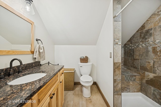 bathroom featuring tiled shower, lofted ceiling, wood-type flooring, and toilet