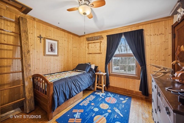 bedroom featuring dark hardwood / wood-style flooring, wooden walls, and ceiling fan