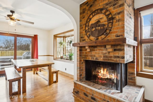 dining room featuring hardwood / wood-style flooring, ceiling fan, a brick fireplace, and a wealth of natural light