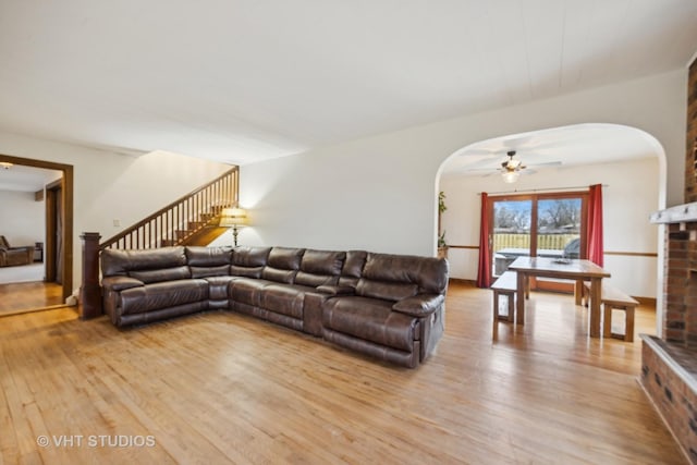 living room featuring a brick fireplace, light hardwood / wood-style flooring, and ceiling fan