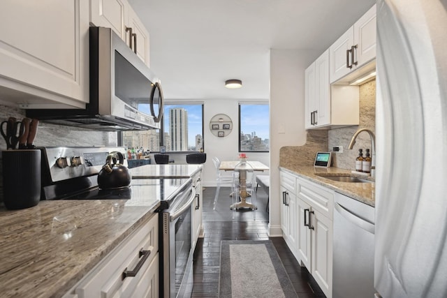 kitchen featuring white cabinetry, appliances with stainless steel finishes, dark hardwood / wood-style flooring, and light stone countertops