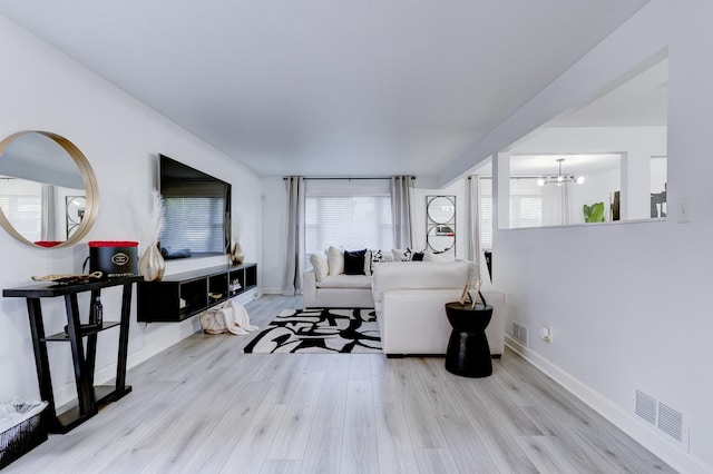 living room featuring light wood-type flooring and a notable chandelier