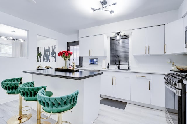 kitchen featuring white cabinetry, sink, a kitchen breakfast bar, black range with gas cooktop, and a notable chandelier