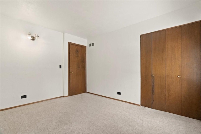 unfurnished bedroom with light colored carpet and a closet