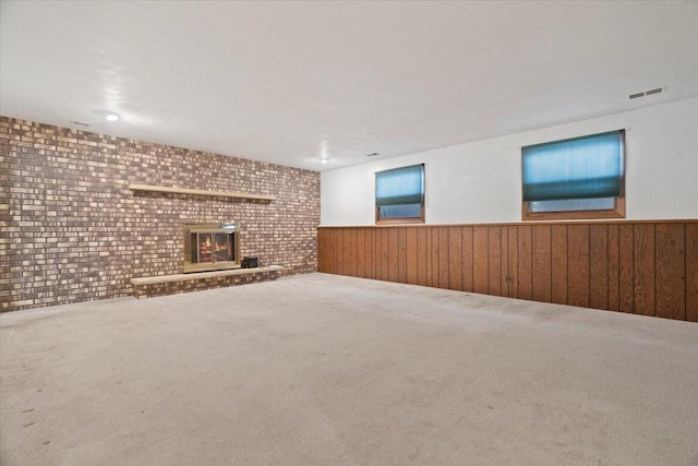 basement featuring a fireplace, wood walls, carpet flooring, and brick wall