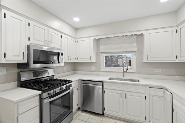 kitchen with sink, white cabinetry, light tile patterned floors, and appliances with stainless steel finishes