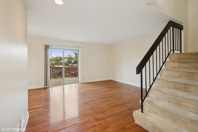 unfurnished living room featuring visible vents, stairway, wood finished floors, and baseboards