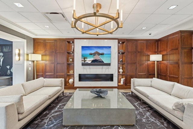 living room with a notable chandelier, built in shelves, and ornamental molding