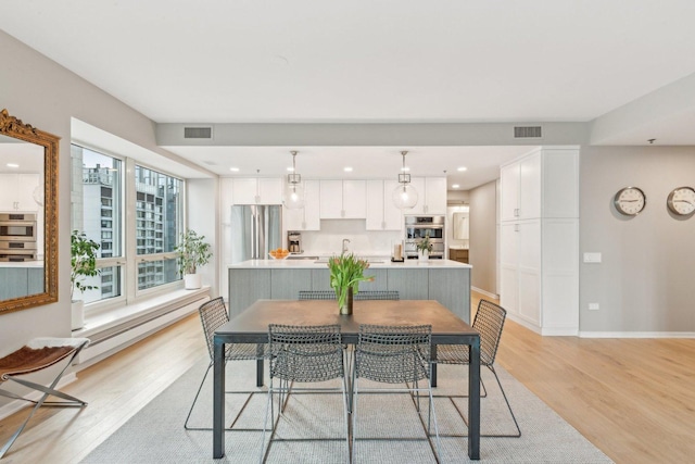 dining area with a baseboard heating unit, a healthy amount of sunlight, and light hardwood / wood-style flooring