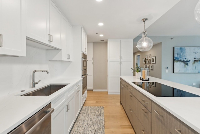 kitchen featuring pendant lighting, sink, black electric stovetop, white cabinets, and stainless steel dishwasher