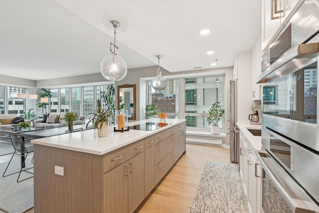 kitchen with a spacious island, a breakfast bar, light wood-type flooring, pendant lighting, and stainless steel appliances