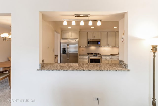 kitchen featuring tasteful backsplash, light stone countertops, stainless steel appliances, and a chandelier