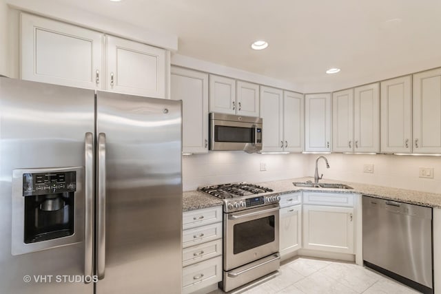 kitchen featuring sink, appliances with stainless steel finishes, light stone countertops, white cabinets, and decorative backsplash