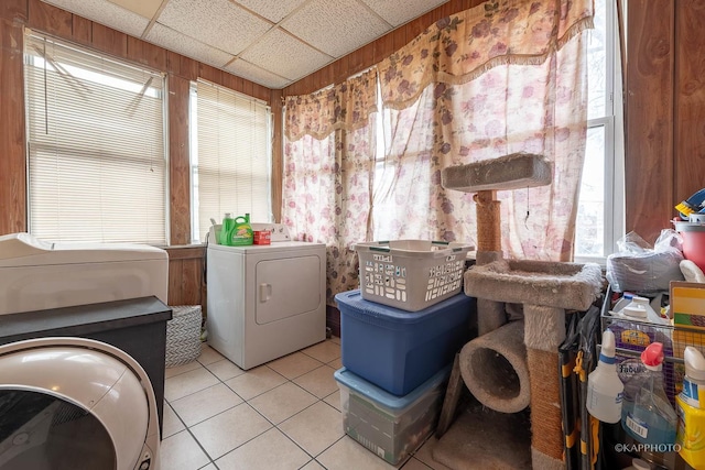 clothes washing area with light tile patterned flooring, washing machine and clothes dryer, and wooden walls