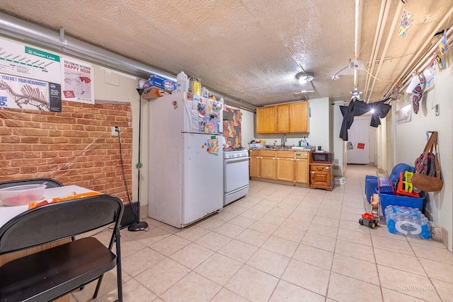 kitchen featuring sink, a textured ceiling, light brown cabinets, white appliances, and brick wall