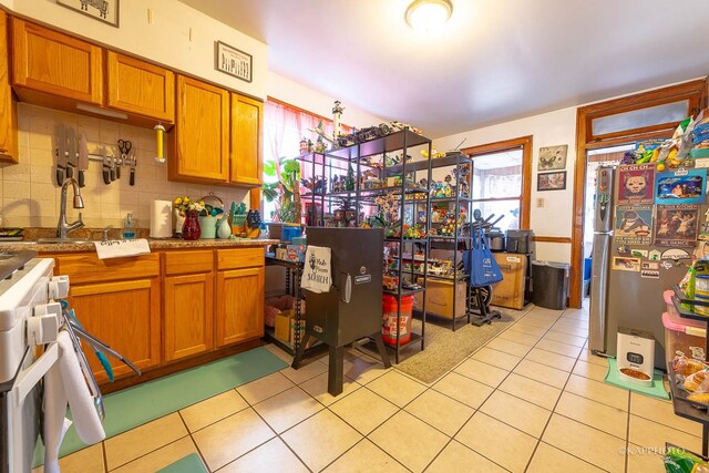 kitchen featuring light tile patterned flooring, white range with gas cooktop, sink, and backsplash