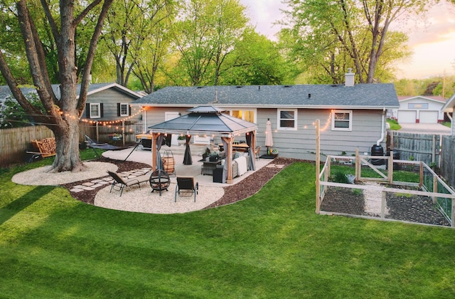 back house at dusk featuring a yard, a gazebo, a patio, and an outdoor fire pit