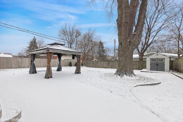 snowy yard with a gazebo and a storage unit