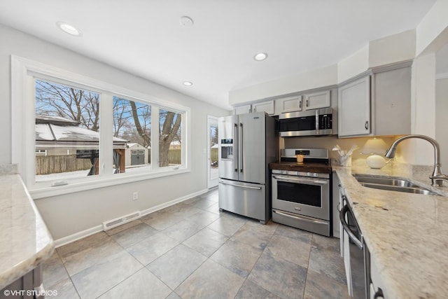 kitchen featuring sink, gray cabinets, stainless steel appliances, and light stone countertops