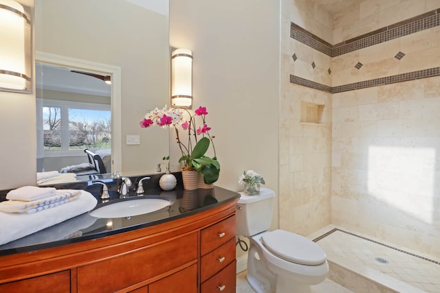 full bath featuring toilet, tiled shower, and vanity