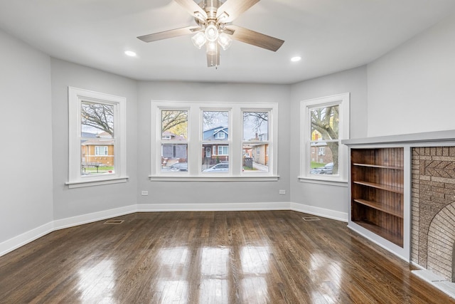 unfurnished living room with a fireplace, ceiling fan, and dark hardwood / wood-style flooring